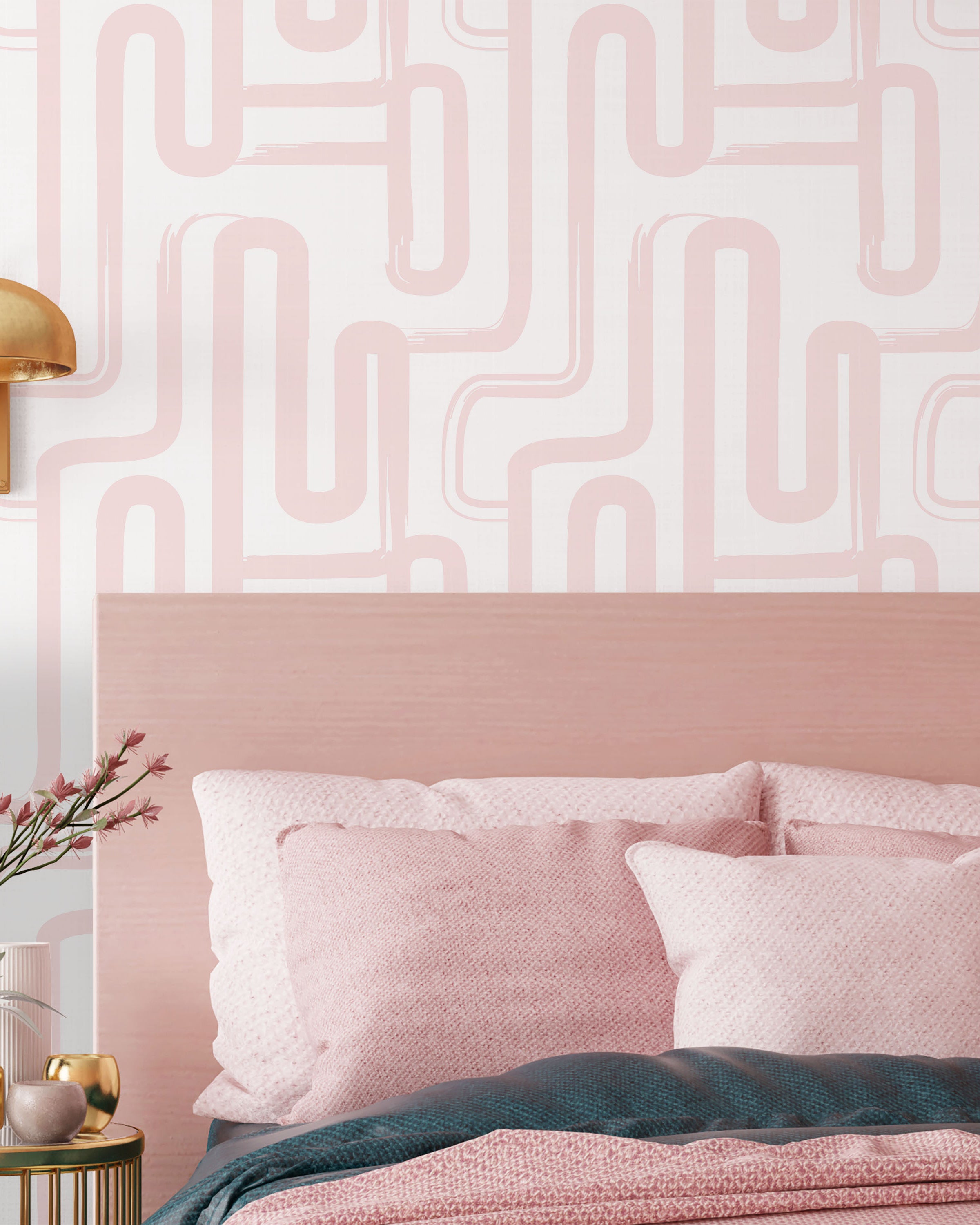 Pink bedroom with geometric wall pattern, gold lamp, and decorative pillows.