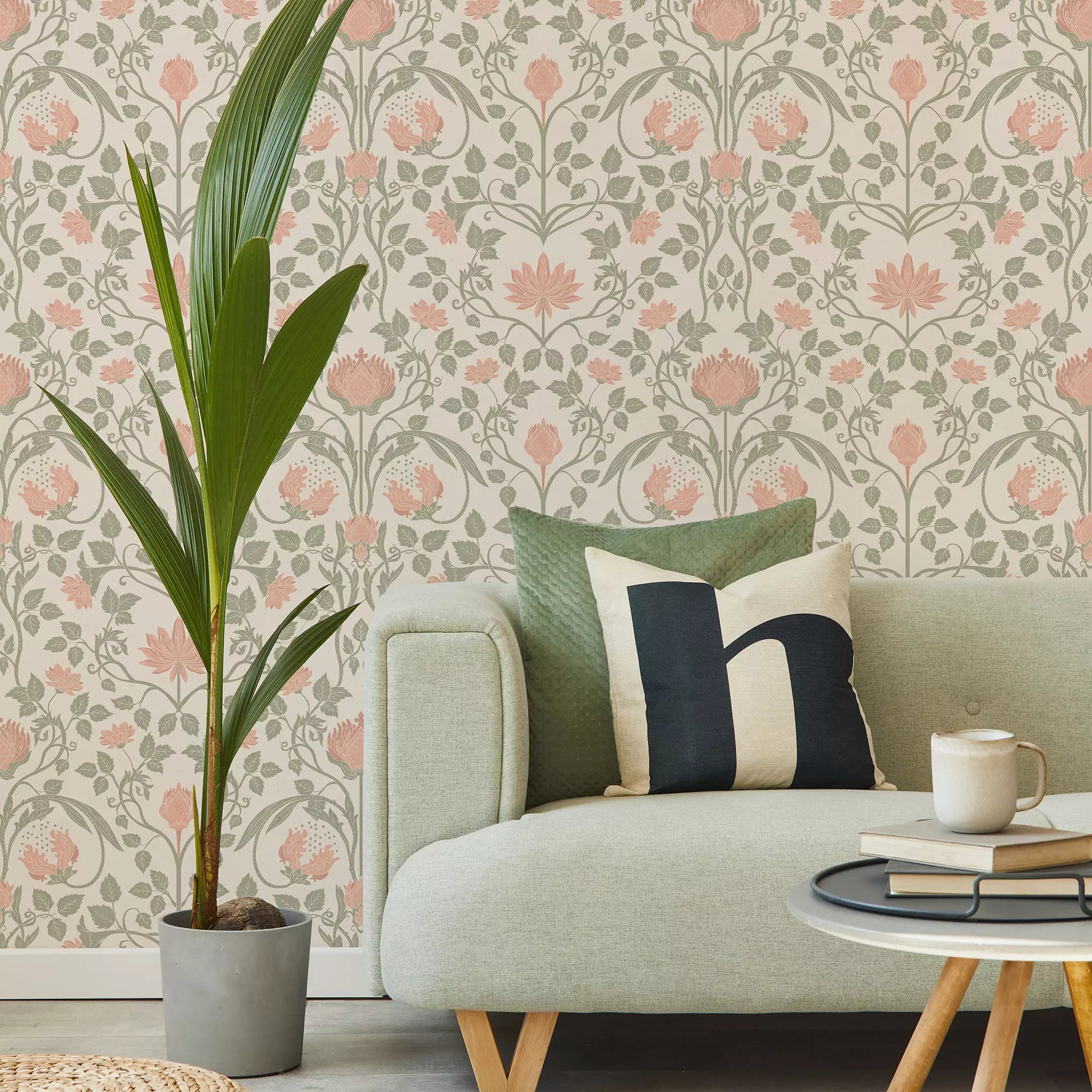 Living room with a sofa, decorative pillows, a plant, and a coffee table against a floral wallpaper.