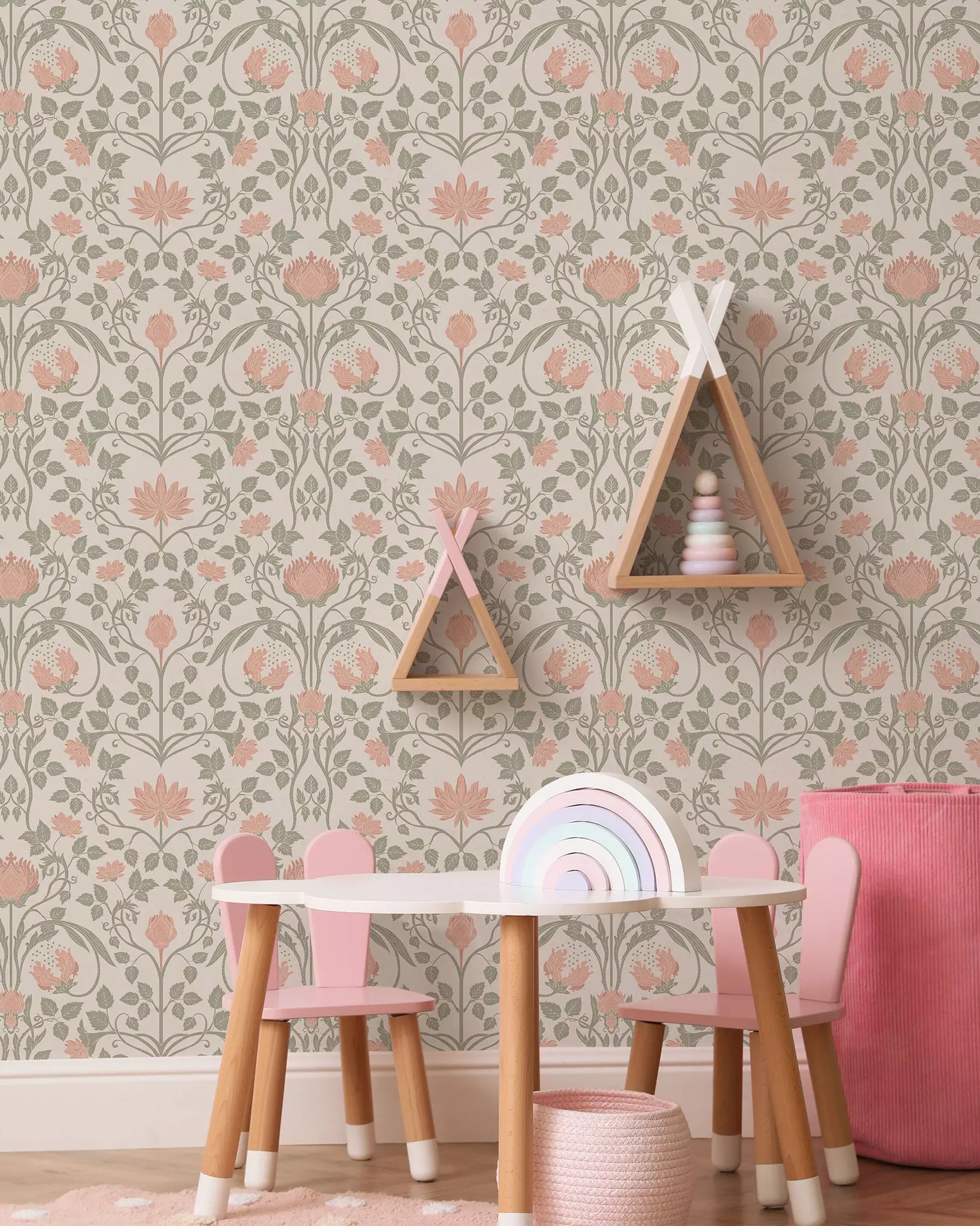 Children's play area with a floral wallpapered wall, pink chairs, and a small table.
