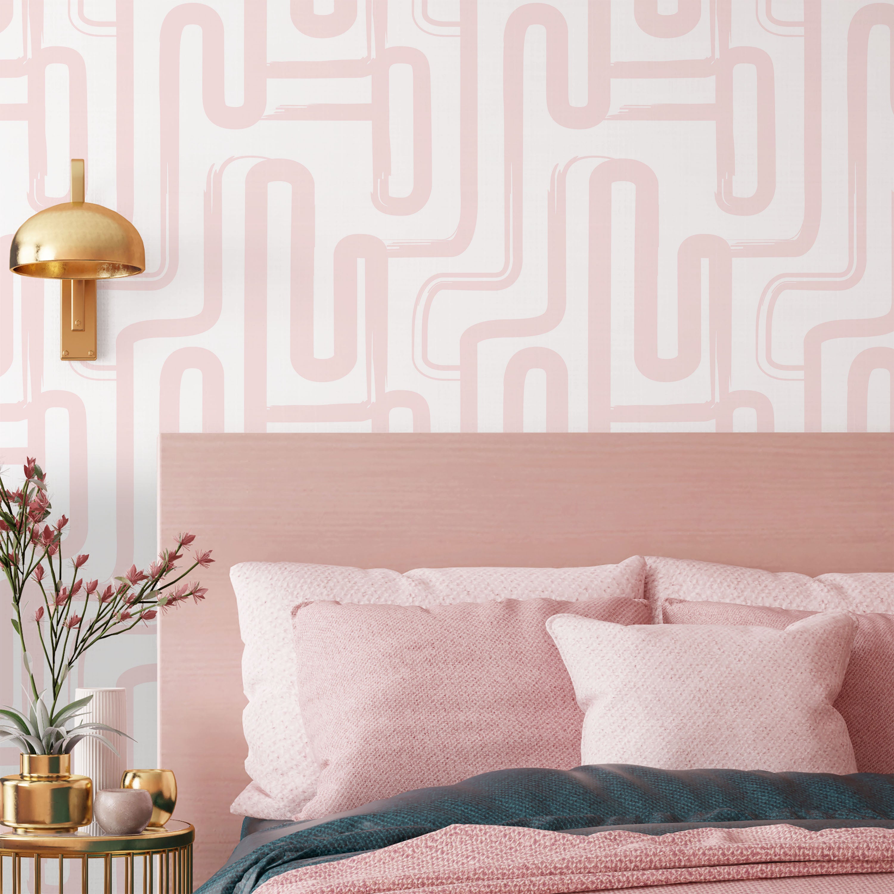 Pink bedroom with geometric wall pattern, gold lamp, and decorative pillows.