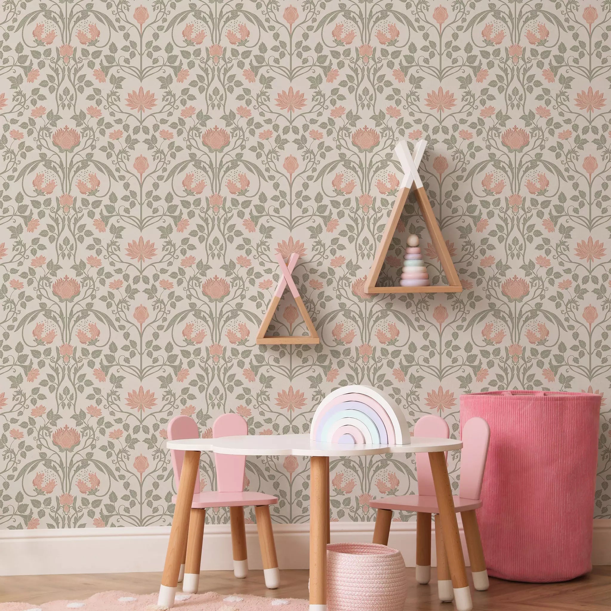 Children's play area with a floral wallpapered wall, pink chairs, and a small table.